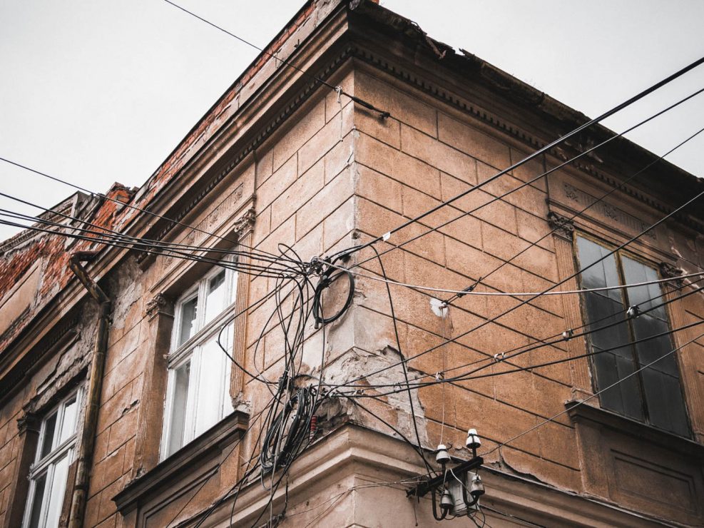 Tangled electrical wires and cables on the corner of an old, weathered building in Timisoara